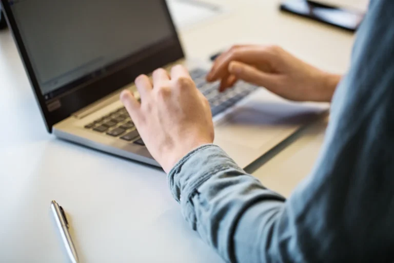 Pessoa digitando em um notebook no escritório, com mão usando o teclado e outra segurando o mouse; contexto de trabalho e tecnologia para comparar hubspot vs salesforce.